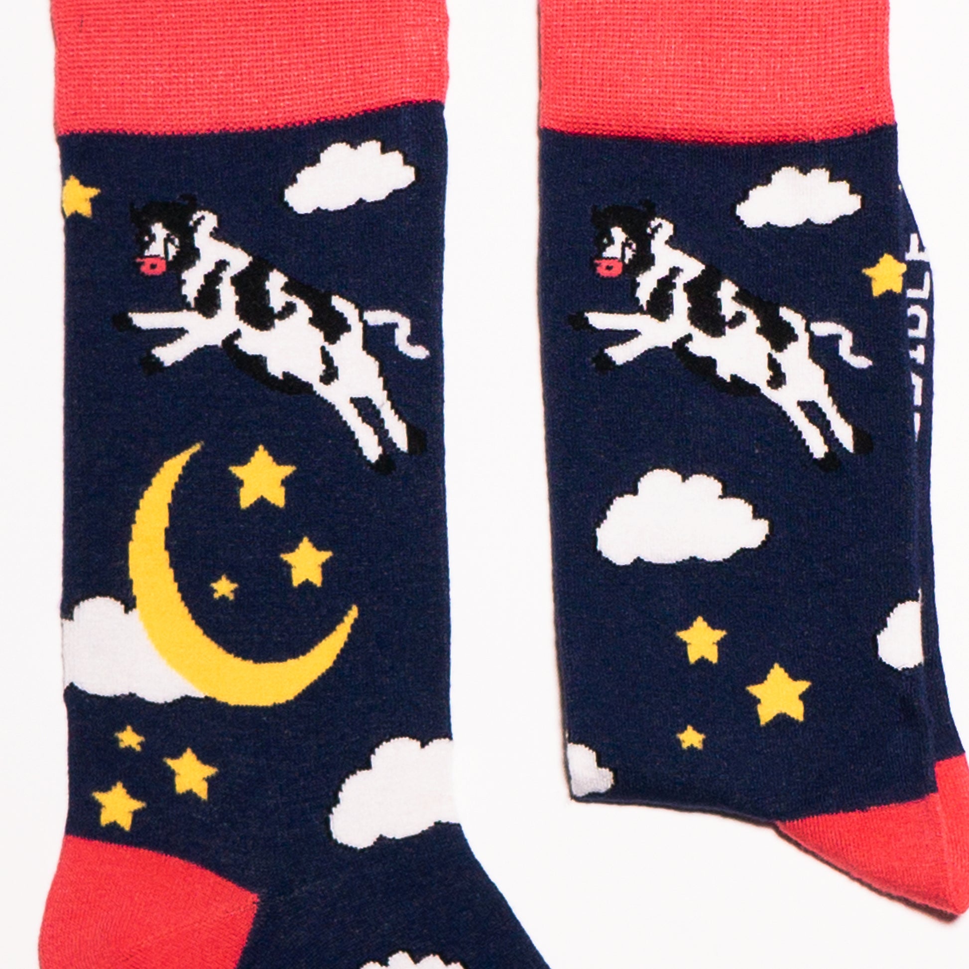 Just like in the nursery rhyme when the cow jumped over the moon. A navy base sets the scene of a fantastical, fun, star-filled night sky. Cows. On Socks. We know!  Available in US Men’s 4-8 and 8-12. Soft. Strong. Sustainable. Comfortable. Incredible Socks. Cow jumping over the moon socks.