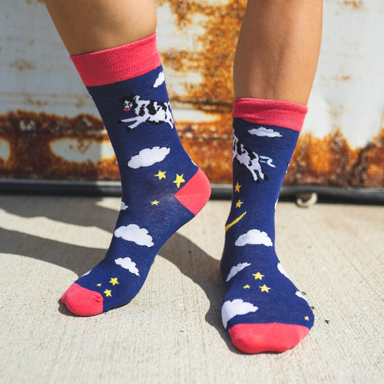 Just like in the nursery rhyme when the cow jumped over the moon. A navy base sets the scene of a fantastical, fun, star-filled night sky. Cows. On Socks. We know!  Available in US Men’s 4-8 and 8-12. Soft. Strong. Sustainable. Comfortable. Incredible Socks. Cow jumping over the moon socks.